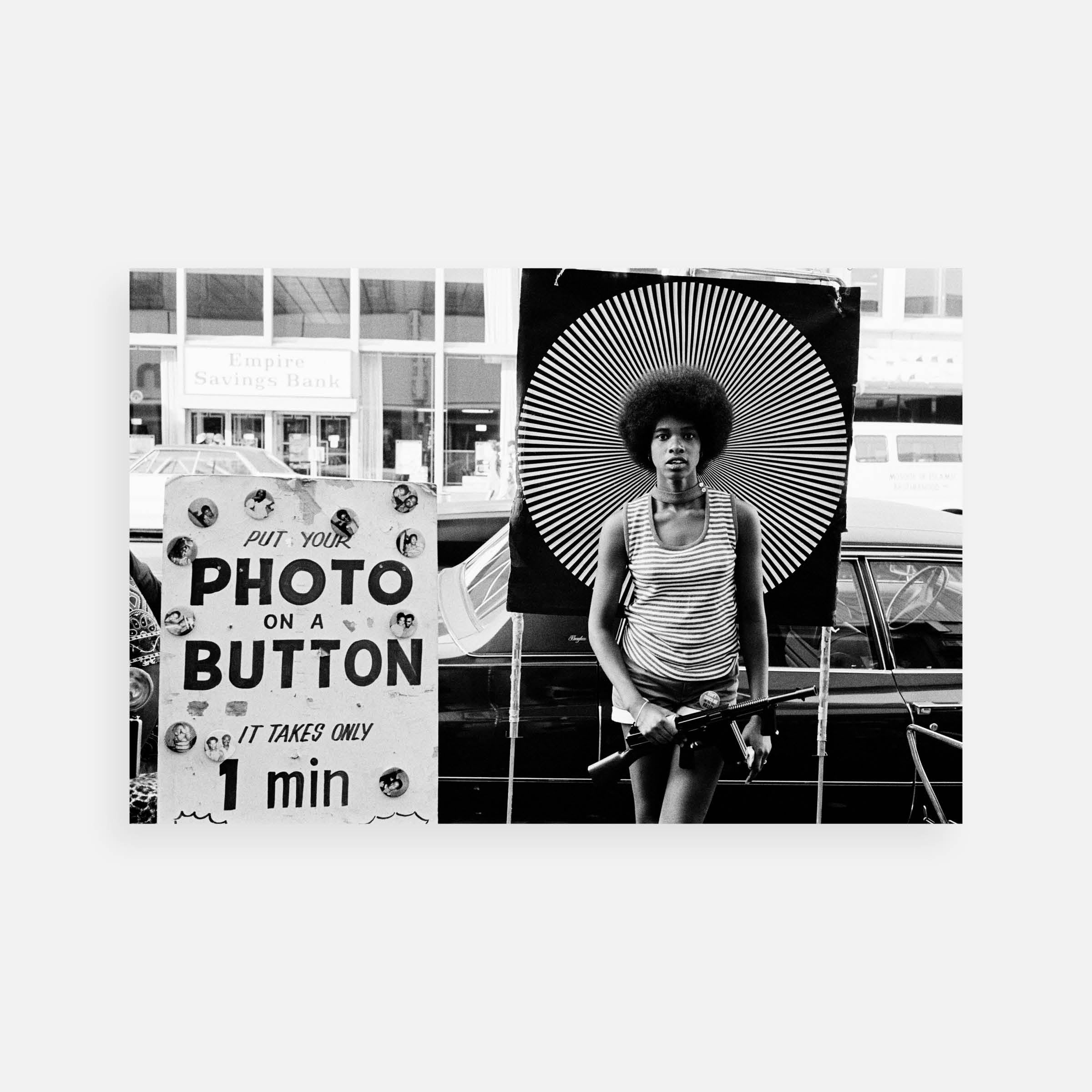 Ernest Cole: Woman poses with a “Photo on a Button” sign, Harlem, New York, 1968–71